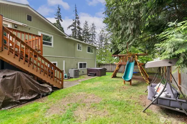 Backyard with playset, heat pump and hot tub.