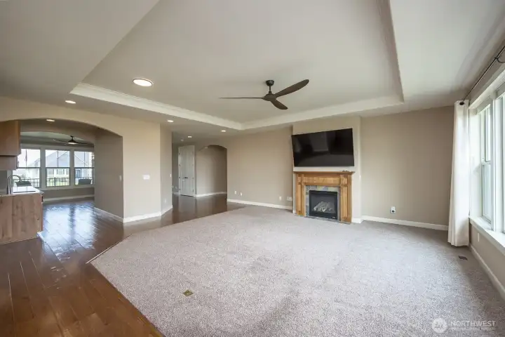 A view of the Great Room and Propane fireplace, entrance to the Primary and Bedroom 2, the Formal Dining Room and Wet Bar.