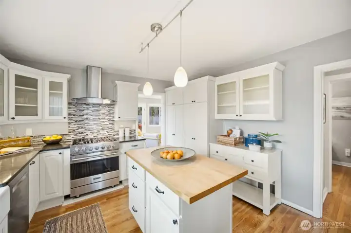 Pretty kitchen features a gas Viking range, stainless Bosch dishwasher, ample cabinets covered with quartz counters and nice butcherblock covered island.
