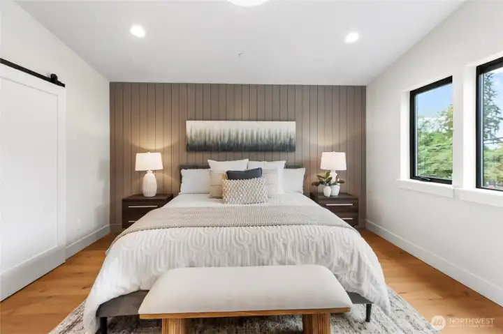 This large bedroom combines soft textures, warm wood accents, and abundant natural light to create a serene and spacious retreat.