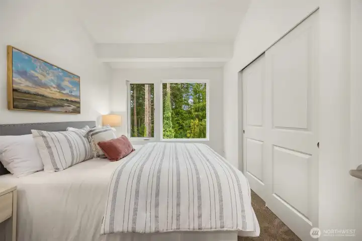 Primary bedroom with a peaceful outlook, looking out to lush, temperate forest views.