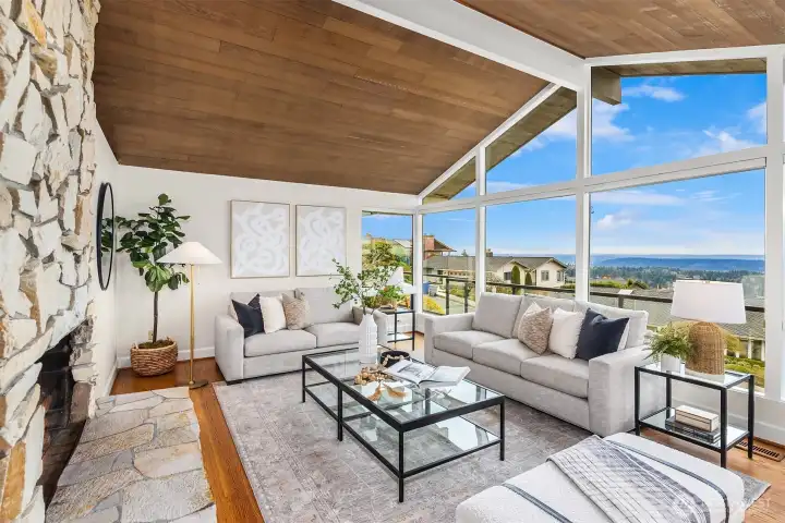 A large living room with cedar lined, vaulted ceilings, fireplace and lots of windows.