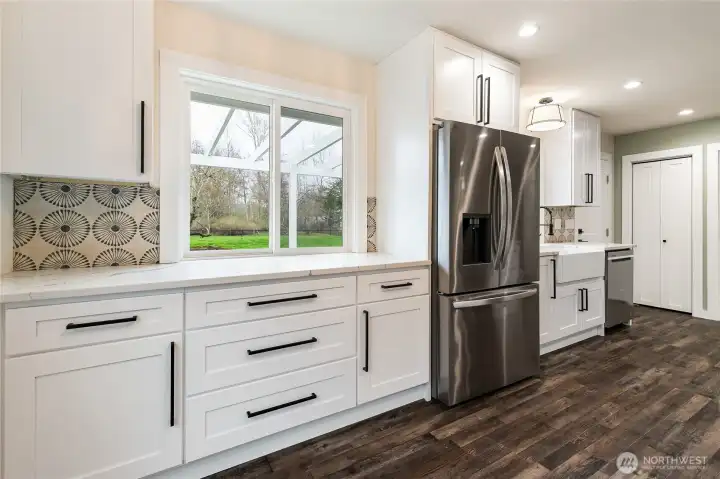 To the right of the fridge, there is a hidden trash and recycle receptacle.