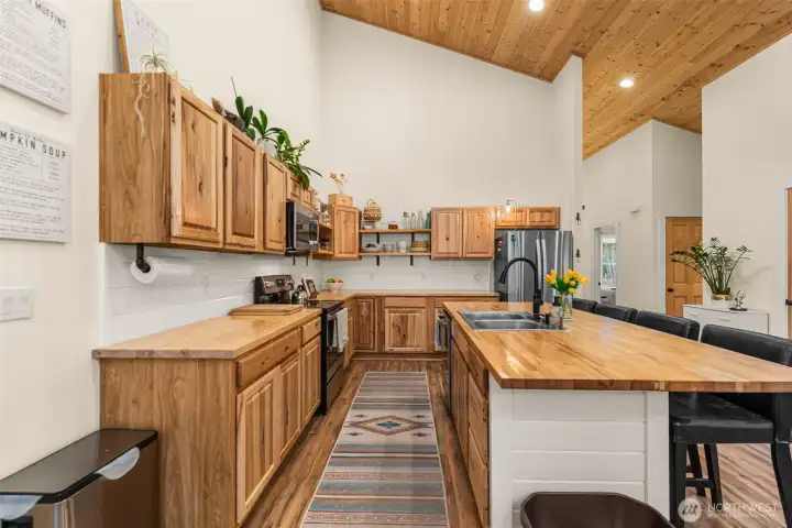 Warm natural wood cabinetry and butcher block countertops bring a refined organic feel to this thoughtfully designed kitchen, where vaulted tongue-and-groove ceilings enhance the sense of openness and light.