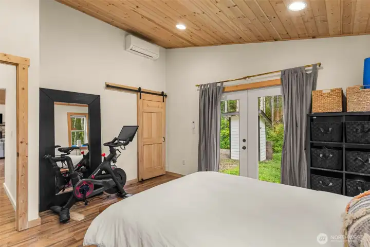 Large windows and glass doors invite soft natural light and offer a seamless connection to the surrounding forested landscape, while the simple, clean design enhances the sense of comfort and relaxation.