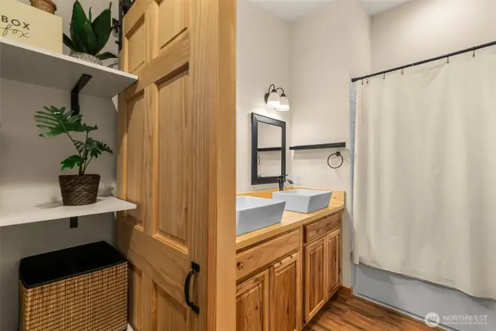 Dual vessel sinks and generous counter space create both functionality and style, while soft lighting and warm wood accents add a calming, spa-like feel