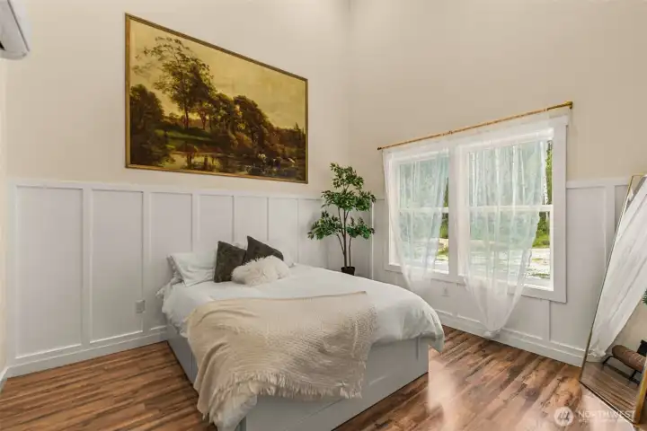 Tall ceilings and expansive windows give this serene bedroom a bright and airy feel, while soft natural light and forest views create a peaceful connection to the outdoors.