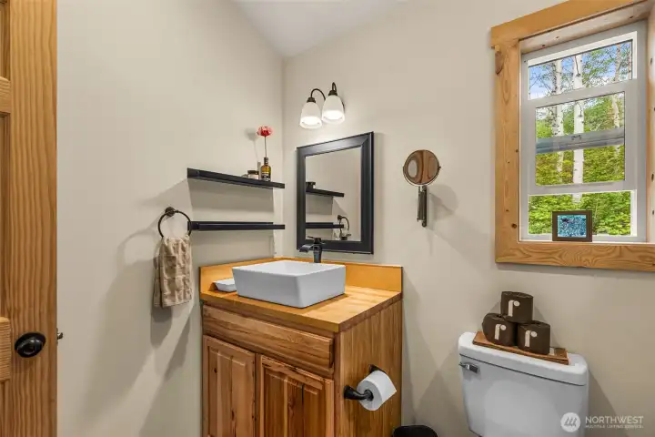 Soft lighting and simple textures bring a calming, spa-inspired feel to the space, while the window invites natural light and peaceful forest views.