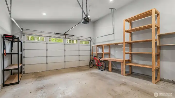 he garage is clean, functional, and thoughtfully designed with built-in shelving, generous storage, and high ceilings that enhance usability