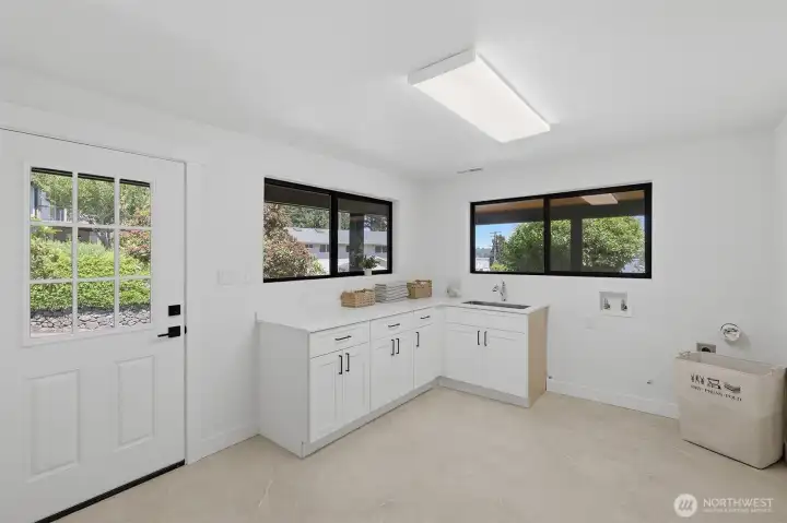 This large, functional utility room features expansive countertops, a deep sink, and ample closet space, providing exceptional storage and organization potential.