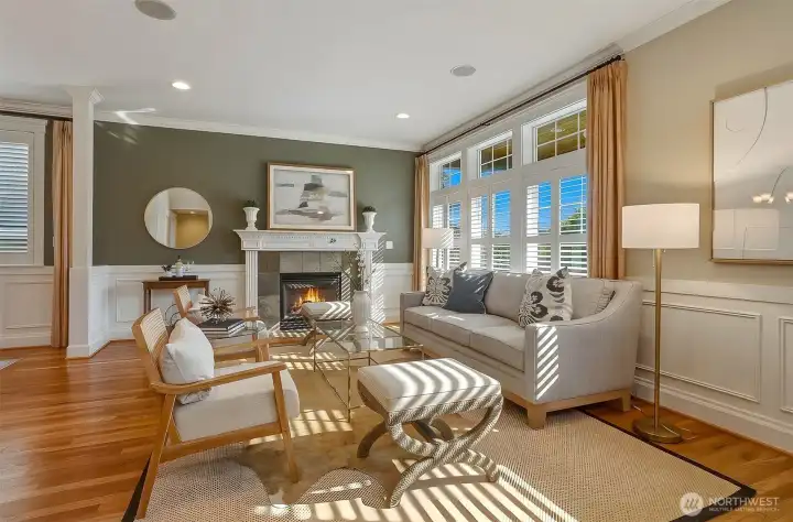 The elegant formal living room features timeless architectural details, including refined crown molding, classic wainscoting, and a handsome gas fireplace that creates a warm, inviting atmosphere.