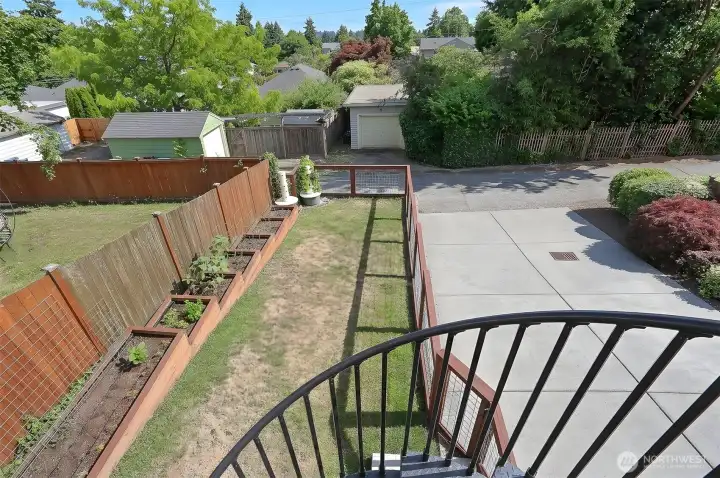 An elegant wrought-iron staircase creates a graceful connection between the private garden and the upper deck.