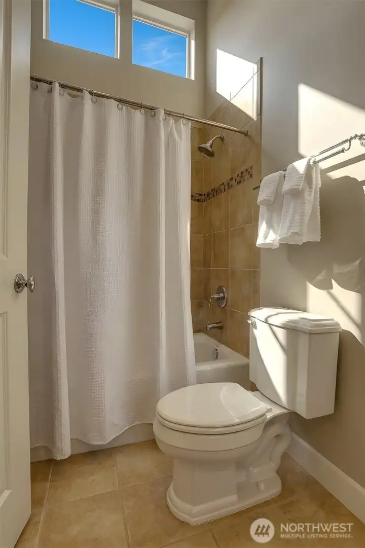 The full guest bathroom offers a dramatic sense of scale with soaring ceilings and thoughtfully designed finishes.