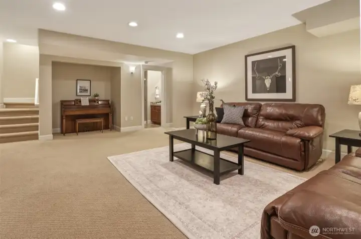 The spacious lower level is designed for flexibility and comfort, featuring a large recreation room with a cozy piano nook that can also serve as a game area or creative space.