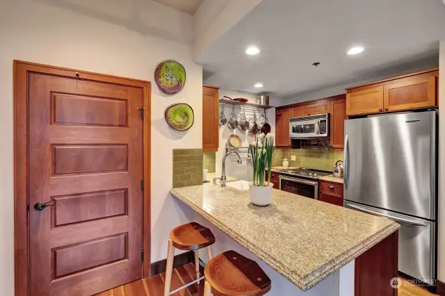 The kitchen features stainless steel appliances, granite countertops, cherry cabinetry, and an eating bar for easy and convenient meals