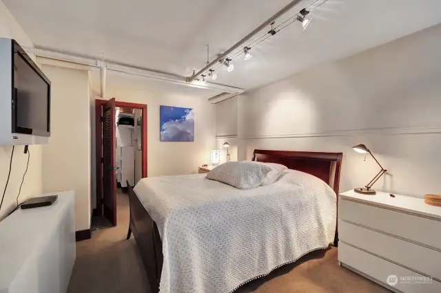 The bedroom with a large walk-in closet featuring ample shelving, adjustable rods, and soft lighting