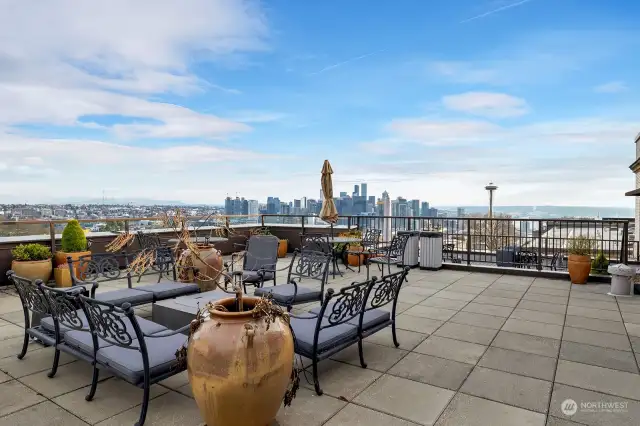 The rooftop deck featuring cozy lounge areas, perfect for relaxation or entertaining, with breathtaking panoramic views of the Seattle skyline, Puget Sound, and stunning sunsets over the surrounding landscape