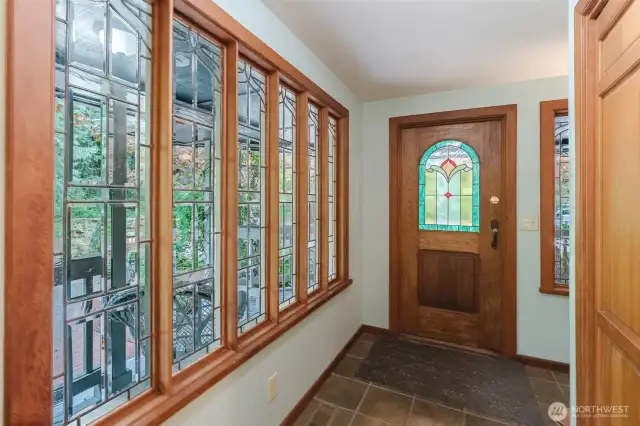 The foyer is adorned with a leaded glass window and a stained glass door.