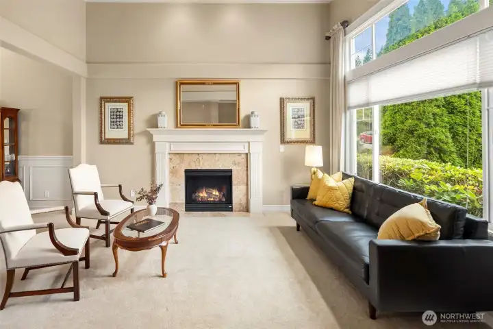 Formal Living Room with beautiful gas log fireplace, dramatic high ceilings, and large picture window looking into the front yard.