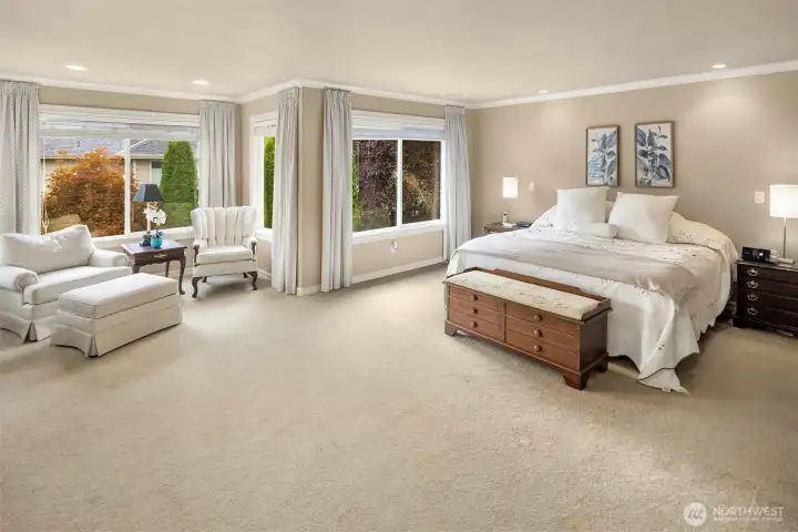 The spacious master bedroom suite with sitting area to the left. It looks out over the backyard. Nice wood window  blinds included.