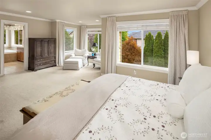 The primary bedroom with big windows looking out to the backyard, nice sitting area or desk area, crown molding, and a Luxurious 5 piece bathroom