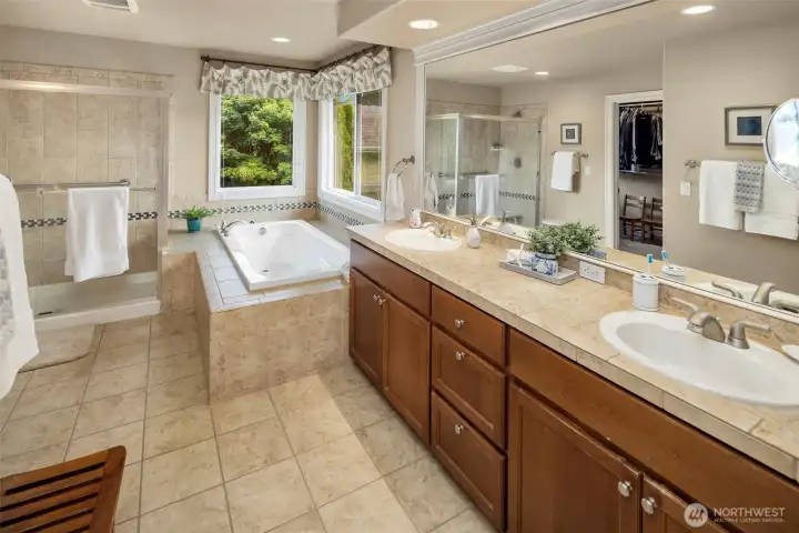 This luxurious Primary Suite Bathroom features dual sinks, nice tile counters and floors, deep soaking tub, a large  separate shower, toilet room, and big walk-in closet with custom shelving & organizers!