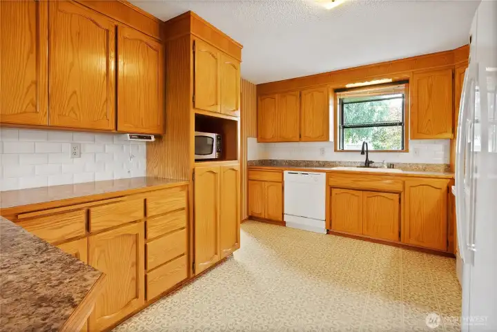 Bay window in kitchen with all appliances included and generous cabinetry for storage.