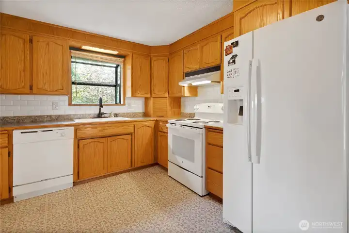 Bay window in kitchen with all appliances included and generous cabinetry for storage.