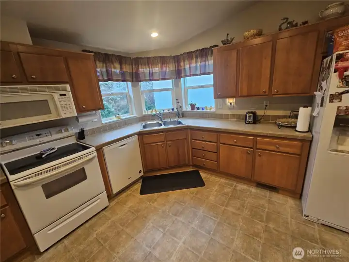 Spacious kitchen with lots counter space and light from three windows.