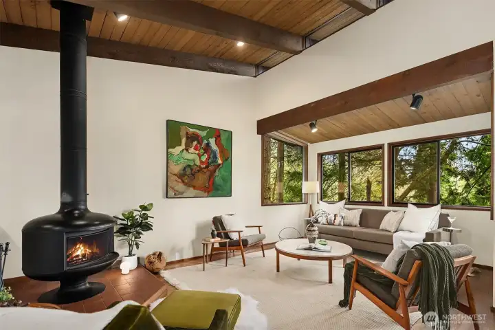 An iconic MCM freestanding fireplace takes center stage in the living room, where differing ceiling heights deliver a delicious combination of drama and coziness.
