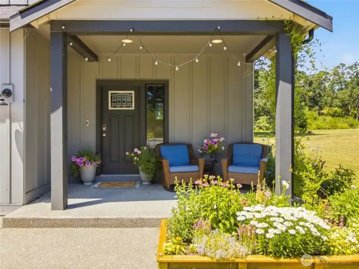 Covered front patio, surrounded by thriving wildflower bed with drip irrigation.