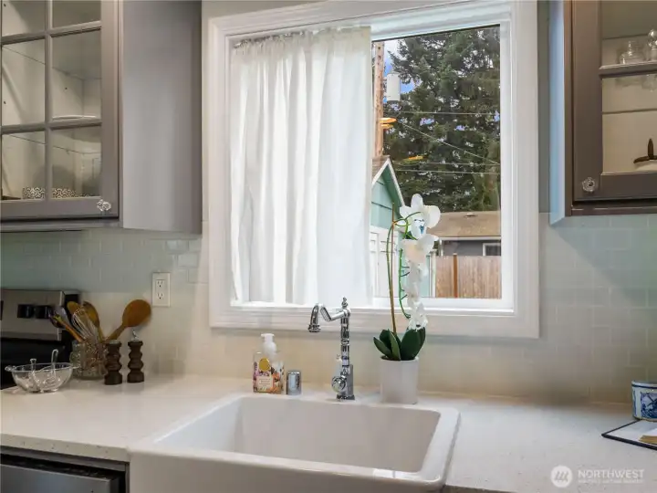 Wash dishes in this white apron farm sink with a view of the right-side yard.