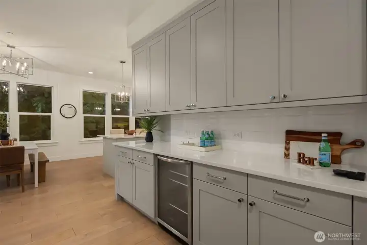 Wrap around cabinetry spills into the great room with a built-in beverage refrigerator, making this a perfect entertainment bar for  snacks and drinks.