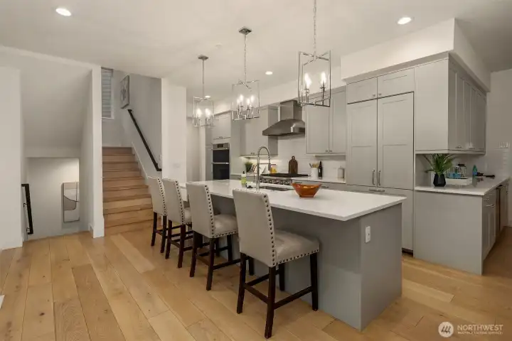 In the heart of the home, a large center island with lovely pendant lighting is designed to be both beautiful and functional, a natural gathering place for family and friends to hang out.