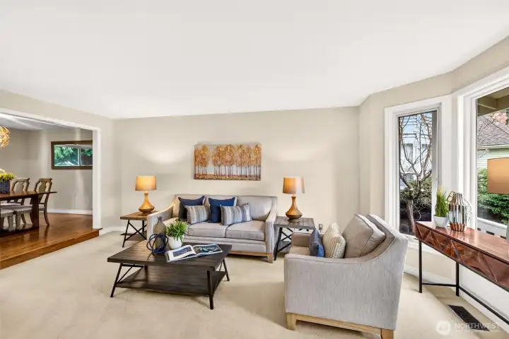 The living room is generous in size and filled with natural light through large windows. A soft carpeted surface adds comfort and makes this space ideal for relaxing or hosting.