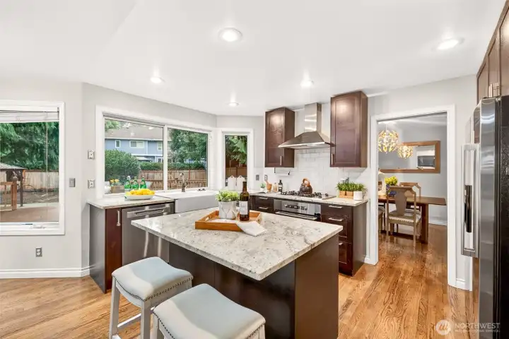 The updated kitchen centers around a generous island with slab granite counters, perfect for prep, serving, and casual meals. A farmhouse sink and expansive windows bring in natural light and offer a peaceful view to the deck and backyard.