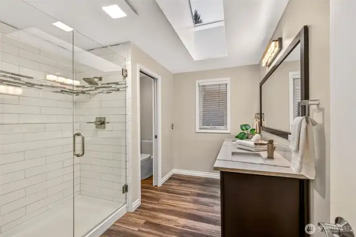 The remodeled primary bath delivers a fresh, spa inspired look with a sleek glass shower, modern finishes, and beautiful natural light from overhead skylights. A long vanity provides excellent counter space and storage, making mornings smoother and more comfortable.