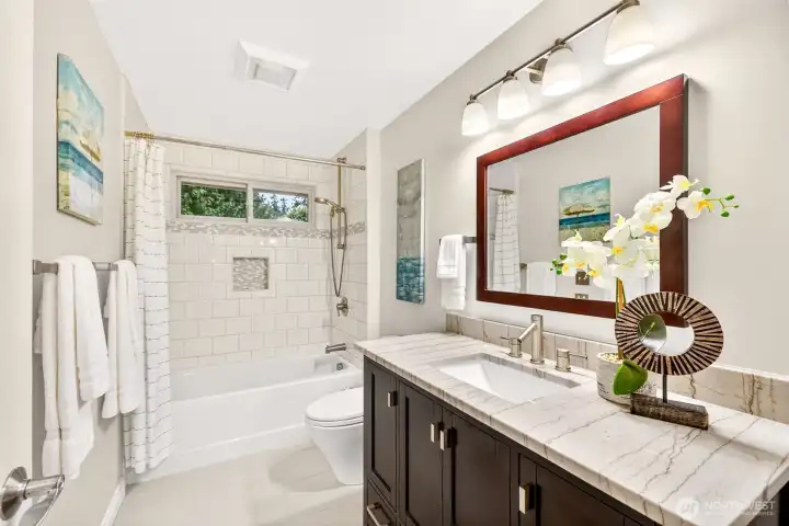 The updated hall bath pairs a refreshed vanity and modern lighting with a bright tub and shower surround. Clean lines and practical storage highlight easy living and maintenance.