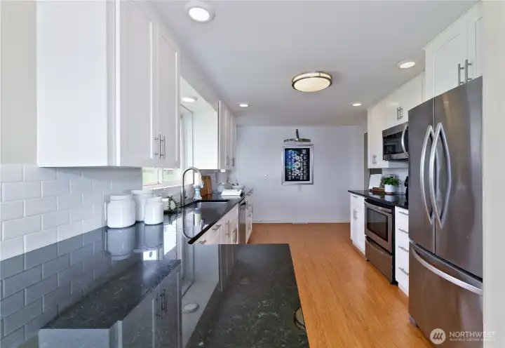 Updated galley style kitchen with white shaker cabinets, quartz counter tops, stainless steel appliances.