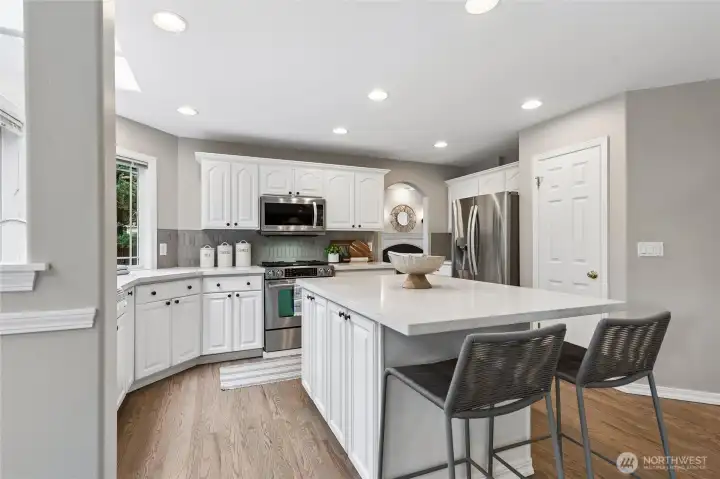 A walk-in pantry adds even more storage space. Hardwood floors flow seamlessly throughout these areas and connect back to the entry through the hallway enhancing the homes cohesive design.
