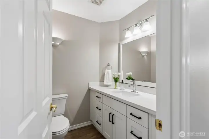 The powder bath has been thoughtfully updated with refinished hardwood floor, new cabinetry, quartz countertops and backsplash, upgraded mirror and new toilet - offering a fresh modern feel.