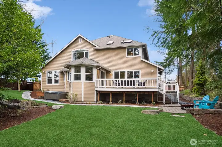 the large deck with stairs to & from back yard and stone patio and stone retaining wall and path that leads back along the eastside to the gated fence to front driveway.