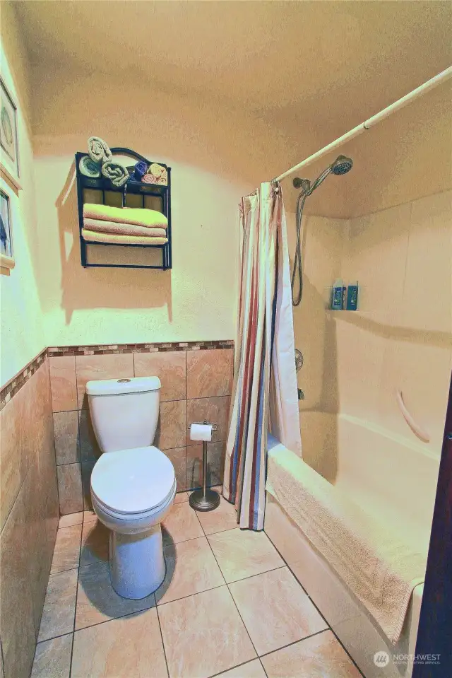 The guest bathroom offers a full bath with shower and custom tile floors and half walls for ease of maintenance.