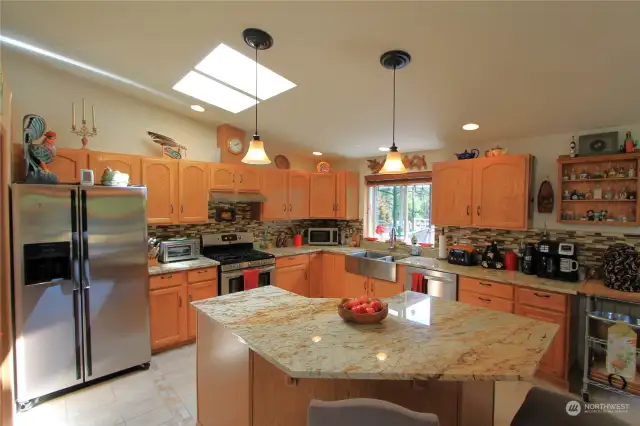 This beautiful kitchen features a central island, perfect for meal prep and casual dining.  Skylights flood the space with natural light, creating an inviting and airy atmosphere for cooking and entertaining.