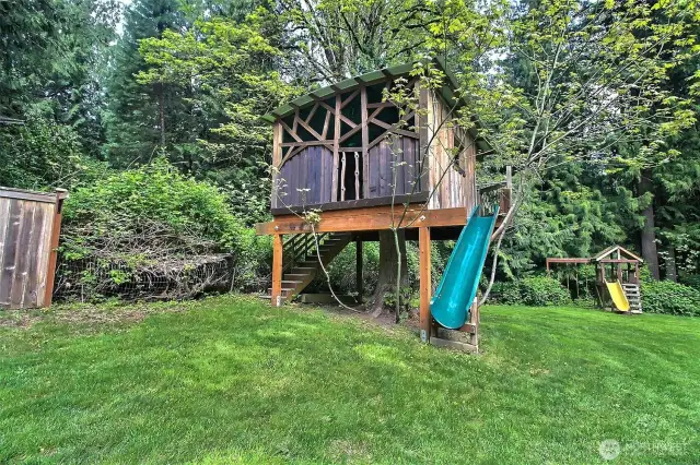 Unique tree house with slide and another play structure in the background for endless hours of fun!