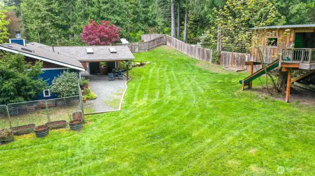 Part of the back yard showcasing the covered patio area, the dog run, and absolutely awesome Tree house