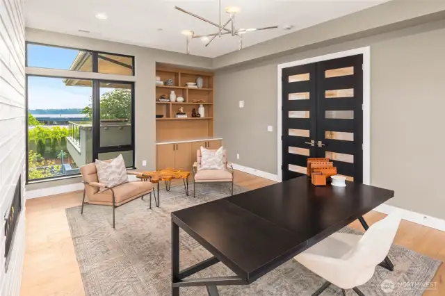 Library features custom built in rift oak shelves with lower cabinets and slab top. Custom built stained rift oak double doors and designer light fixture finish out the space