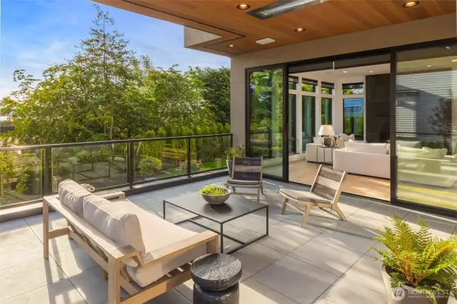 Expansive covered area with fine line cedar ceiling and flush mounted ceiling heaters elevate the inside/outside living