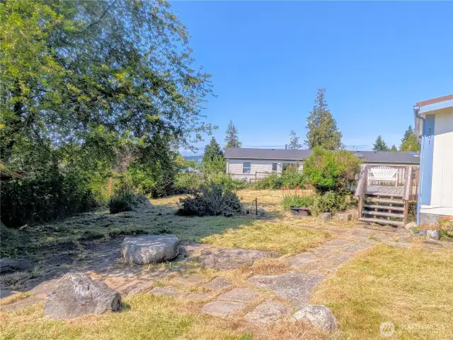 Yard with pathway to the front door and stone seating area.