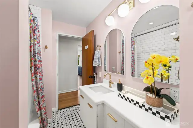Stylishly renovated bathroom featuring tub and shower tile that extends to the ceiling.